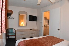 A bedroom with a bed, a dresser, a chair, a TV, and a mirror. - Blue Water Motel (Wildwood Crest)