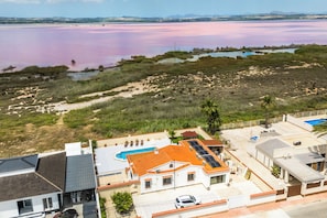 A residential area with houses, a swimming pool, and a large body of water. - Villa Mariposa Azul with a private pool, terrace, and views of the Salt Lake (Torrevieja)