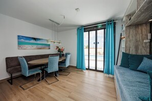 A modern room with a wooden dining table, blue chairs, a sofa, and a large window with curtains. - Villa Mariposa Azul with a private pool, terrace, and views of the Salt Lake (Torrevieja)