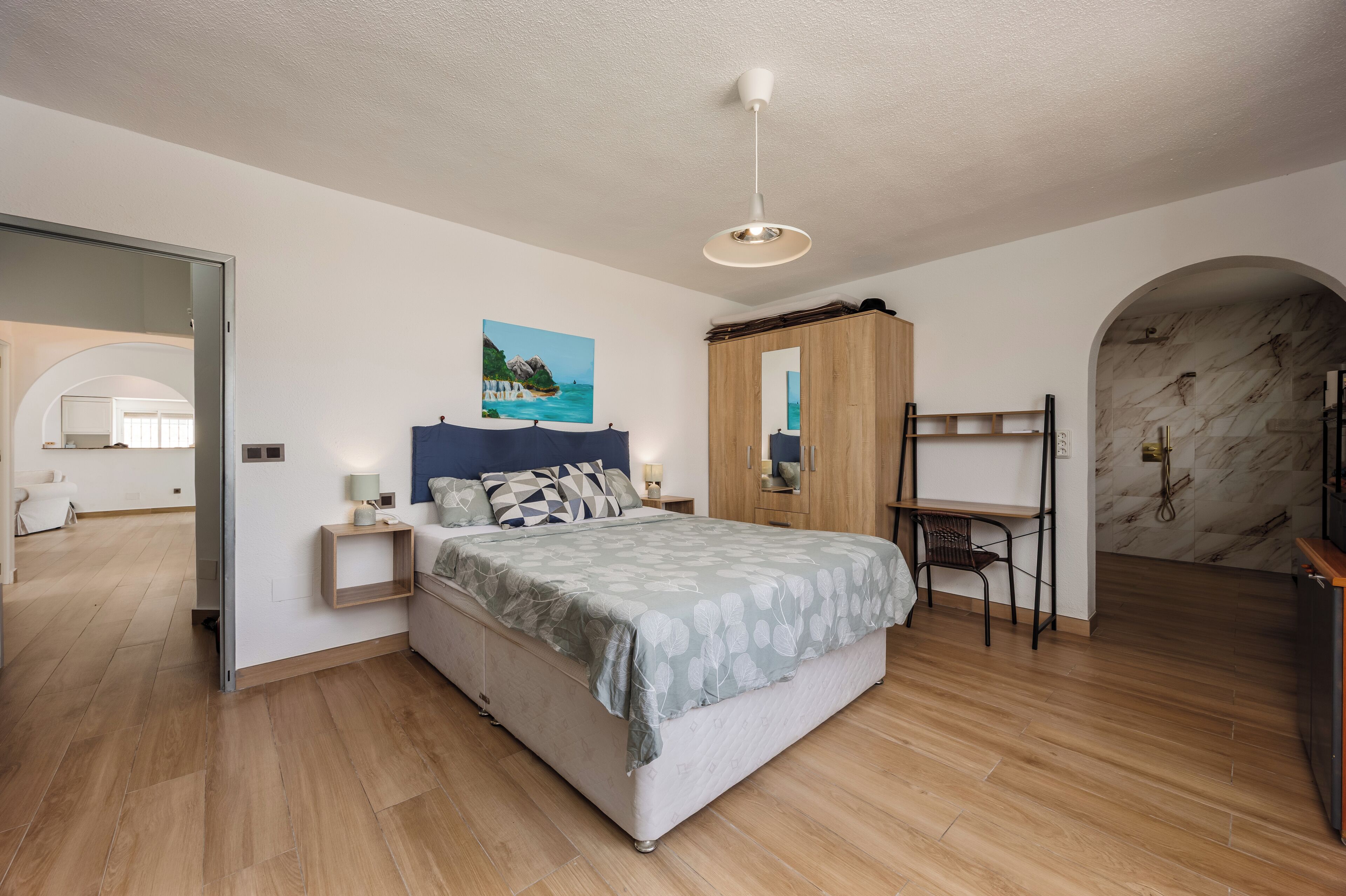 Une chambre à coucher comprenant un lit, un bureau, une chaise, une armoire et un miroir.