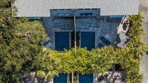 An aerial view of a hotel with a central swimming pool surrounded by palm trees and lounge chairs. - Walk Everywhere! 8BR Duplex w/ 2 Pools, Sleeps 16+ (Folly Beach)