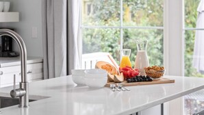 A kitchen counter with breakfast items, a sink, and a window with a view of greenery.
