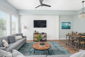 Ein modernes Wohnzimmer mit einer Couch, Couchtisch, Fernseher, Esstisch und Stühlen.