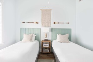 Ein Schlafzimmer mit zwei Betten, einem hölzernen Nachttisch, einem Wandbehang aus Makramee und zwei Holzlöffeln an der Wand.