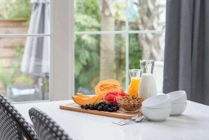 Ein Frühstückstisch mit Früchten, einem Glas Orangensaft und einer Milchflasche.