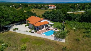 A house with a swimming pool, surrounded by greenery and other houses in the background. - Villa Elssa by Villas Guide (Ližnjan)