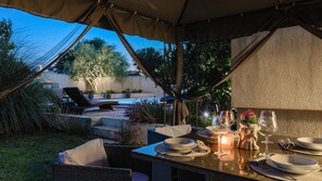 An outdoor dining area with a covered table, chairs, and a pool in the background. - Villa Elssa by Villas Guide (Ližnjan)