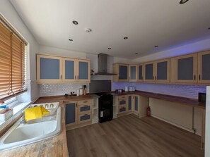 Een keuken met houten kasten, een spoelbak en een fornuis.