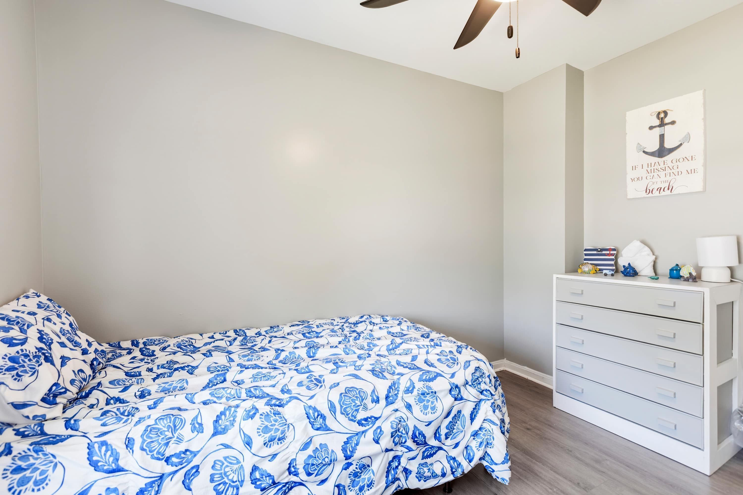 Ein Schlafzimmer mit einem Bett, einer Kommode, einem Deckenventilator und einer Wand mit einem Seefahrer-Poster.