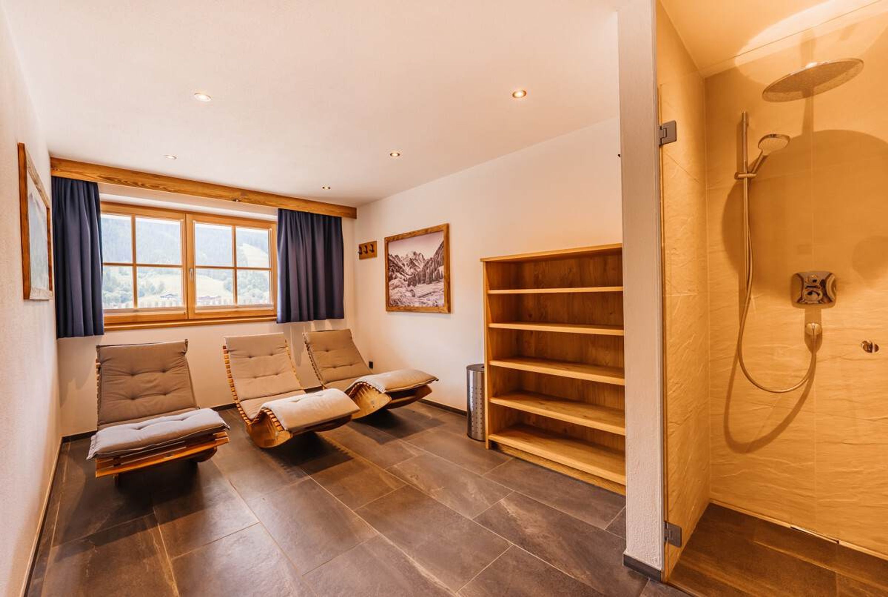 Une pièce dotée d’une grande fenêtre, d’une étagère en bois, d’un fauteuil de massage et d’un espace douche.