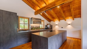 Eine moderne Küche mit einer großen Kochinsel, Holzbalkendecke und eingebauten Geräten.