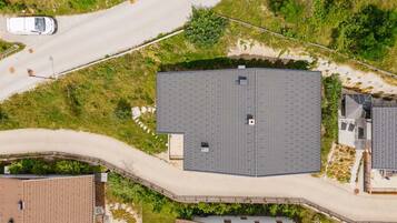 A large, rectangular building with a flat roof, surrounded by a paved driveway and a road.