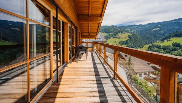 Ein Holzbalkon mit großen Fenstern und Blick auf ein Tal.
