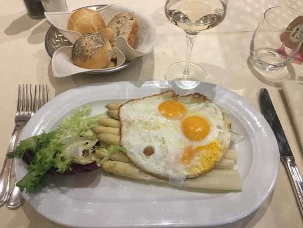 Un plato con huevos, pasta y ensalada, acompañado de pan y un vaso de agua.