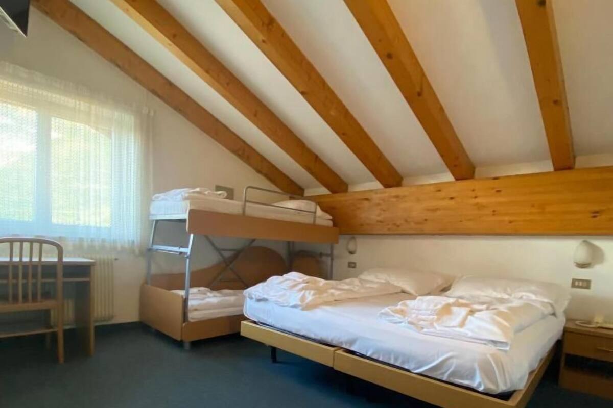 A room with a bunk bed, a desk, a chair, and a radiator.