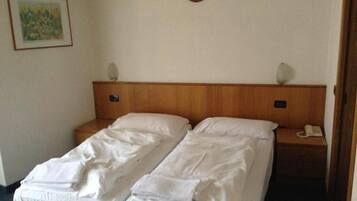 Ein Doppelbett mit weißer Bettwäsche, ein Holz-Kopfteil, Nachttischlampen, ein Telefon und ein Bild an der Wand.