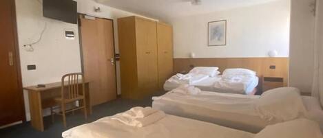 Une chambre d’hôtel avec deux lits, un bureau, une chaise et une armoire.