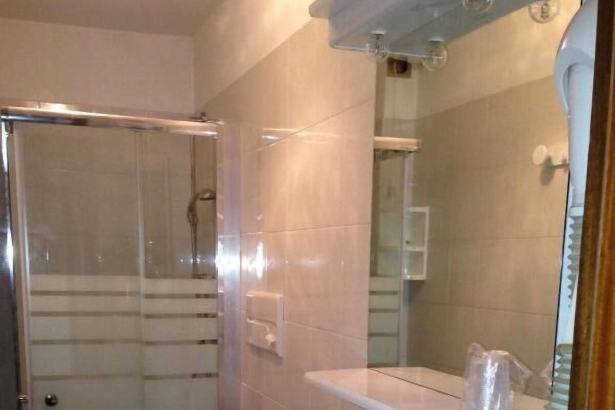 A bathroom with a glass-enclosed shower, a sink, a toilet, and a mirror.