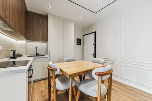 Eine moderne Küche mit einem Holzespeisetisch und Stühlen, weißen Schränken und einem eingebauten Backofen.