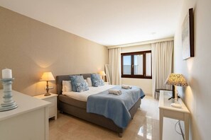 Ein Schlafzimmer mit Bett, Nachttischen, einem Fenster und Blick ins Freie.