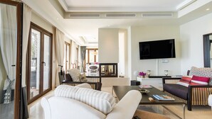 Ein modernes Wohnzimmer mit Sofa, Couchtisch, Fernseher und einem Essbereich mit Stühlen und Tisch.