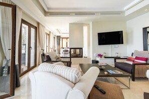 Ein modernes Wohnzimmer mit Sofa, Couchtisch, Fernseher und einem Essbereich mit Stühlen und Tisch.