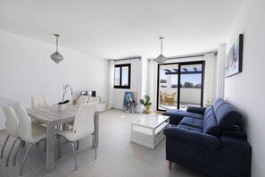 A modern living room with a dining area, large windows, and a balcony. - ESTEPONA SUNSETS - BRAND-NEW MODERN 3-BEDROOM APARTMENT (Estepona)
