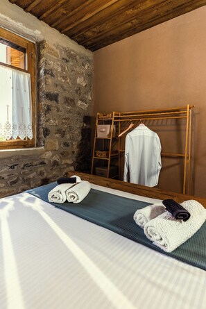 Una habitación con cama, una escalera de madera, un espejo y una ventana con cortinas.