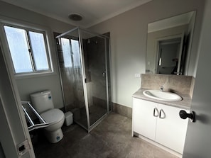 A modern bathroom with a toilet, shower, and sink.