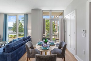 A dining area with a round table set for four, a sofa, and a view of the outdoors.