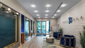 A modern reception area with a glass door entrance, a reception desk, and a seating area with blue upholstered chairs.