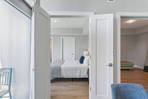 A bedroom with a bed, a chair, and a door leading to another room.