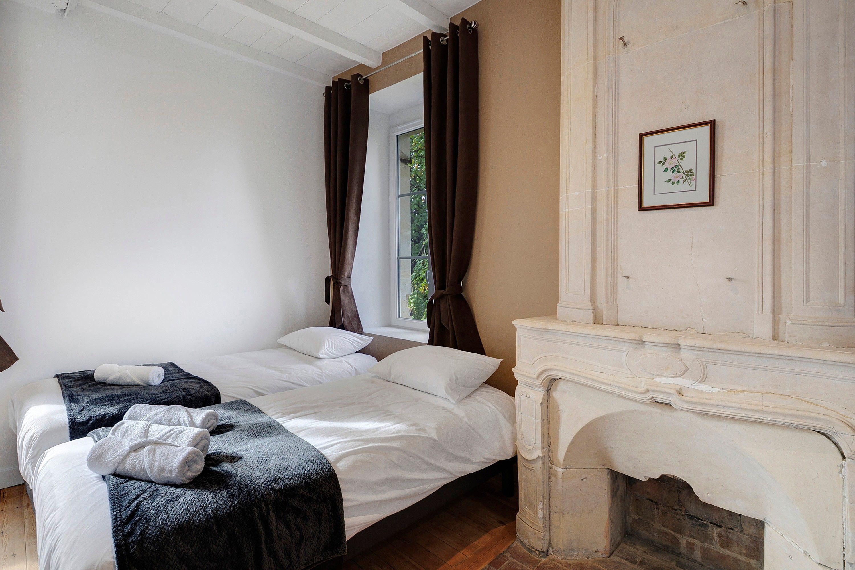 A bedroom with a bed, a fireplace, and a window with curtains.