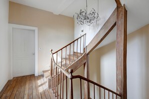 Eine Holztreppe mit einem Chandelier, einer weißen Tür und einem Holzboden.