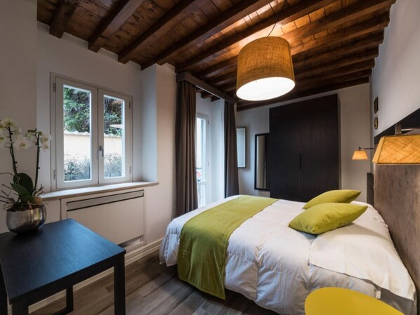 Un dormitorio con cama, ventana, mesa y lámpara colgante.