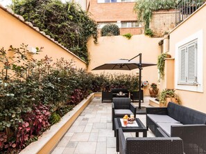 A patio with outdoor furniture, a table with fruit, and a large umbrella. - Dolcevita Panisperna 2 – Anita Apartment (Rome)