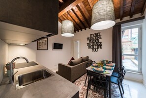 Eine moderne Küche mit integriertem Spülbecken, eine Essecke mit Tisch für vier Personen und ein Wohnbereich mit einer Couch.