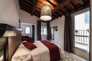Ein Schlafzimmer mit Bett, einer Pendelleuchte, einem Fenster und einem Balkon.
