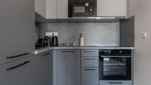 A modern kitchen with grey cabinetry, a built-in microwave, a coffee maker, and a stove.