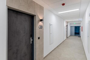 Ein Flur mit einer Tür, einer Wandleuchte und einem Rauchmelder.