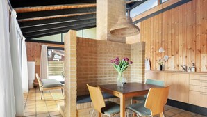 Un comedor con pared de ladrillo, techo de madera y una mesa con sillas.