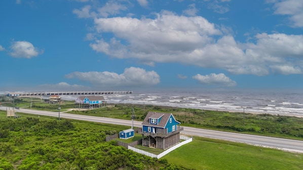 A coastal house with a deck, a pier in the background, and a road leading to it. - H2O Getaway: 3  BR, 2  BA House in Gilchrist, Sleeps 10 (Gilchrist)
