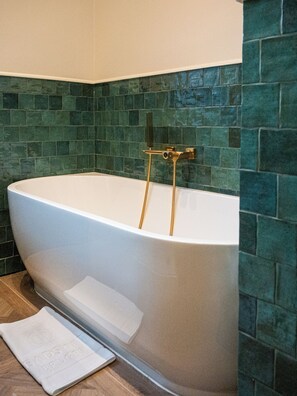 Un baño moderno con una bañera independiente, un cabezal de ducha y una pared de azulejos.