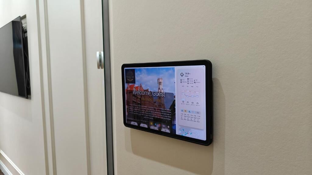 Een digitaal scherm aan een muur met een welkomstboodschap en een overzicht van voorzieningen.