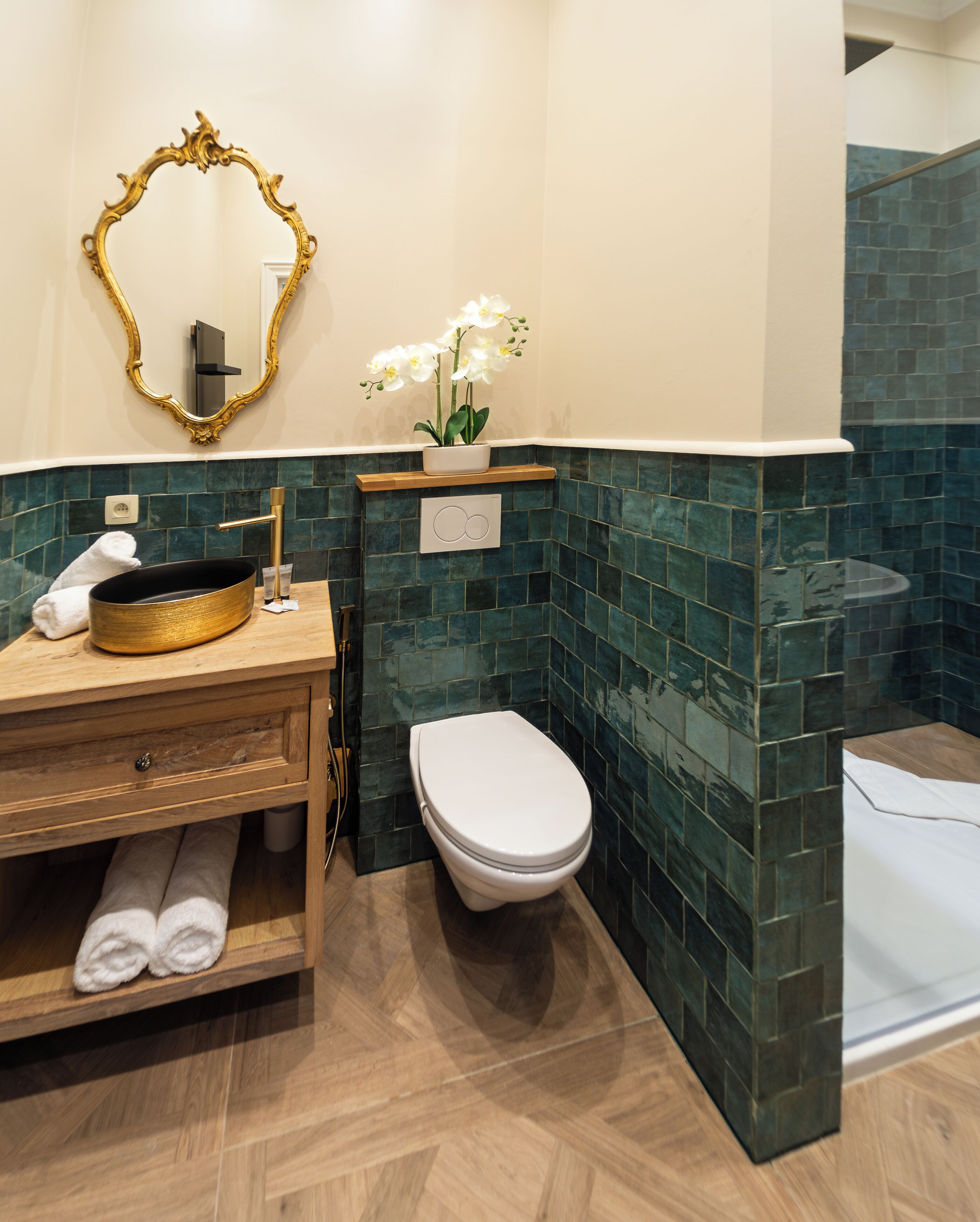 Een badkamer met een houten wastafelmeubel, een wit toilet en een spiegel met een sierlijk lijstwerk.