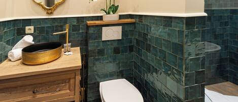 A bathroom with a wooden vanity, a white toilet, and a mirror with an ornate frame.