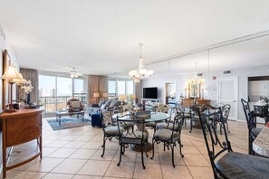 Ein geräumiger Wohnbereich mit Esstisch, Stühlen, einem Fernseher und einem Balkon mit Aussicht.