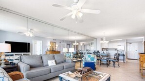 A spacious living room with a sofa, coffee table, and dining area with chairs and a table. - Terrace At Pelican Beach 602 2 Bedroom Home (Destin)