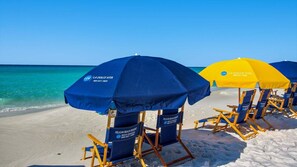 Strandstühle und Sonnenschirme mit 'La Dolce Vita'-Branding auf einem Sandstrand.