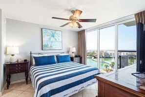 Ein Hotelzimmer mit Bett, Deckenventilator, großem Fenster mit Aussicht, Nachttisch und Schreibtisch.